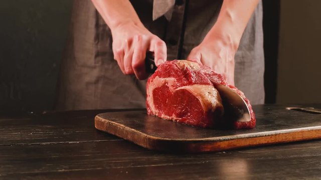 cook cuts raw meat for steaks