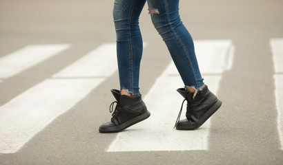 close up of woman legs walking on crosswalk. 
