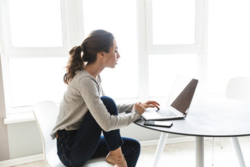 Attractive smiling young woman working on laptop