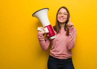 Young cute woman holding a megaphone showing number one