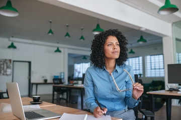 Smiling businesswoman writing ideas in a notebook at her desk