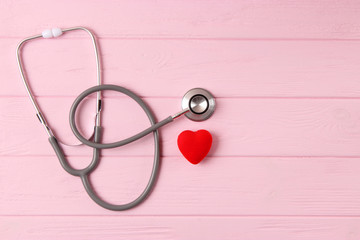 Stethoscope and heart on wooden color background. Health, medicine