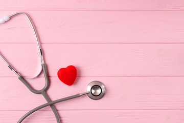 Stethoscope and heart on wooden color background. Health, medicine