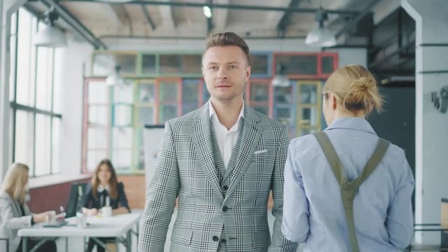 A young business man walks in the office, accidentally bumps into another employee-girl and apologizes to her. Conflict situation. Creative business space. Coworking