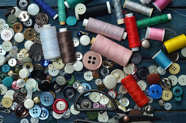 Fototapeta na wymiar A lot of sewing buttons and thread on a wooden background