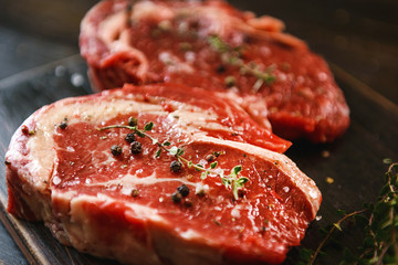 two raw marbled beef steaks in olive oil and spices ready for frying. dinner party concept