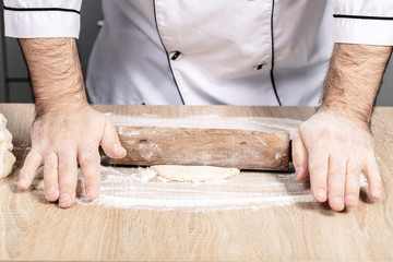 male cook kneads dough on the table