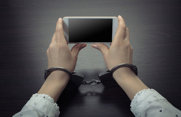handcuffed hands with a mobile phone