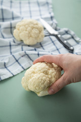 Frau bei Zubereitung Weißen Blumenkohl auf Geschirrtuch mit Messer auf Pastell Grün Hintergrund