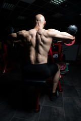 Fototapeta na wymiar Bodybuilder Doing Heavy Weight Exercise For Shoulders