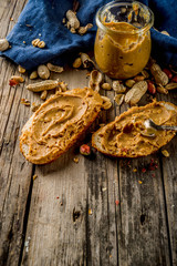 Little peanut butter jar with crunchy peanut butter sandwiches on rustic wooden table