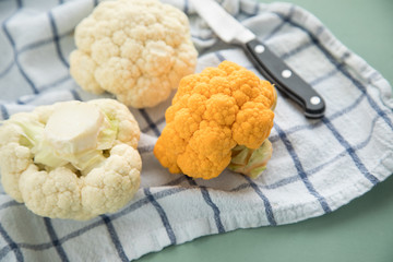 Bunter Blumenkohl Orange und Weiß auf Geschirrtuch mit Messer auf Pastell Grün Hintergrund