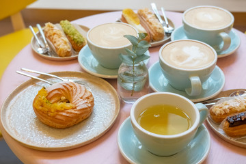 Cafe table with cups of coffee, eclairs and cake