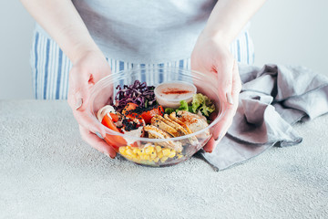 Woman holding healthy lunch bowl with chicken, egg, tomatoes, lettuce, corn, red beans, red cabbage and barbeque sauce. Clean food, dieting nutrition concept. Lifestyle concept. Copy space