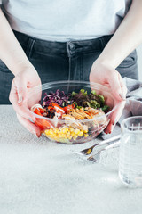 Woman holding healthy lunch bowl with chicken, egg, tomatoes, lettuce, corn, red beans, red cabbage and barbeque sauce. Clean food, dieting nutrition concept. Lifestyle concept. Copy space