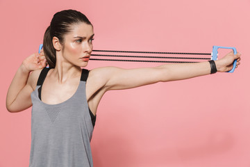 Beautiful young pretty fitness woman make sport exercises with equipment isolated over pink wall background.