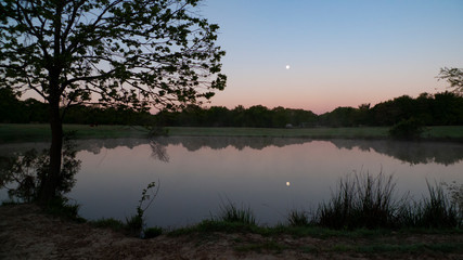 Fototapeta premium Full moon at daybreak, still waters with reflections