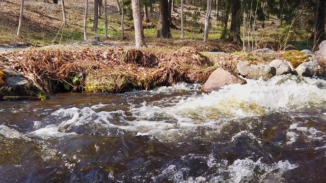Panning shot of fast flowing white foamed stream of water. Filmed in slow motion at 1080p. Camera moves from right to left.