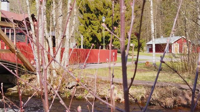 Panning shot of stream of water revealing a walking bridge with water flowing underneath. Filmed in slow motion at 1080p. Camera moves from right to left.