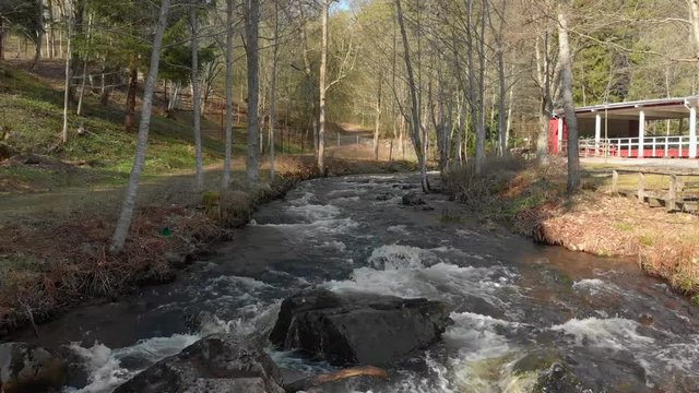 Drone footage flying really close to a fast flowing stream of white foamed water with some big rocks getting closer. Filmed in realtime at 4K.