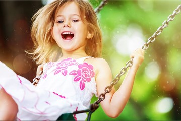 Little child blond girl having fun on a swing