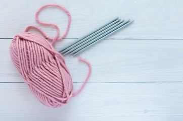 Pink skein with knitting needles isolated on white wooden background, knitting mittens or socks on 5 needles