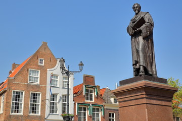 Fototapeta na wymiar Hugo de Groot Monument (dating from 1886) on the main square (Markt) with traditional and colorful facades in the background, Delft, Netherlands