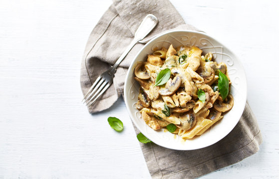 Penne pasta with mushrooms, chicken and cream sauce. Mediterranean cuisine. Flat lay. White background