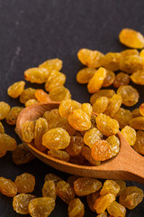 golden raisins on a dark stone background