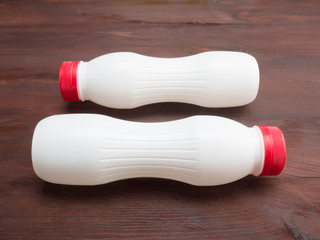 Two plastic white bottle on a brown wooden background