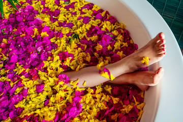 Obraz na płótnie Canvas cropped shot of barefoot woman with flowers, candles, colorful sea salt and bath for nails in beauty salon in Bali hotel tropical vacation.depilation epilation shugaring hair removal concept