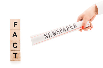 Obraz premium cropped view of woman holding newspaper near wooden blocks with fact lettering isolated on white
