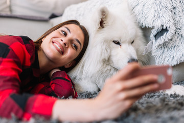 Young woman on floor with dog using phone