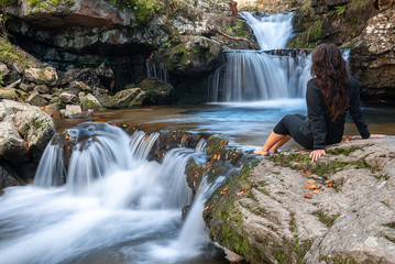 Young girl looks at Puente Ra waterfall, La Rioja, Spain