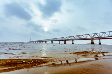Fototapeta premium view of the railway bridge from the water near the river Bank