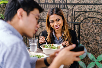 Portrait of two young,poised professionals Asian business people having lunch in a restaurant in Asia. They are eating a nutritious bowl of salad.