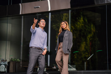 Full body Portrait of two professional businesspeople having a conversation of directions to the city as they stand by the stairs of a building. The man and woman are both professionally dressed.
