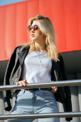 Street portrait of young stylish woman wearing vintage glasses and black jacket