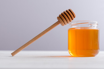 wooden honey spoon and a glass jar with polyfloral golden honey