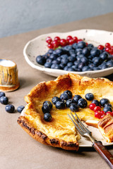 Started eaten fresh baked Dutch baby pancake in ceramic plate with blackberry and red currant...