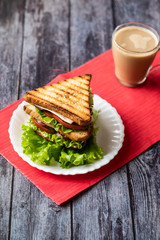 Sandwich with cheese, tomato, cucumber, sausage and lettuce on a wooden background. Vertical orientation
