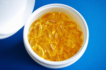 Omega 3 fish oil capsules in plastic bottle on a blue background. Top view. Healthy lifestyle.