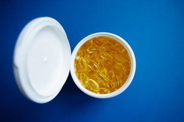 Omega 3 fish oil capsules in plastic bottle on a blue background. Top view. Healthy lifestyle.