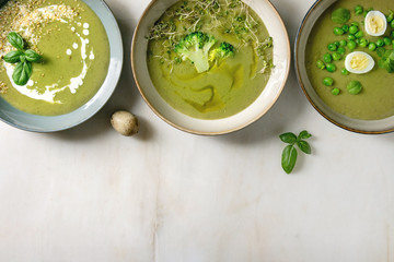 Variety of green vegetable soup asparagus, broccoli and pea, decorated by greens, vegetables, quail...