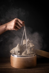 Zongzi, woman going to eat steamed rice dumpling on wood table, famous tasty food in dragon boat festival duanwu design concept, close up, copy space