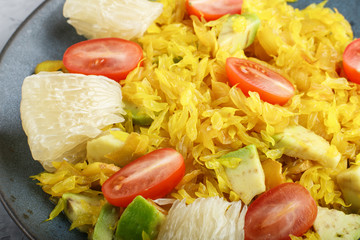 Fried pomelo with tomatoes and avocado on gray concrete background, close up.