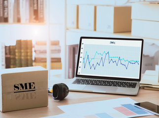 SME or Small and medium-sized enterprises Computer flare sun. Barcode scanner box and statistics.graph on table.