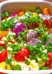 Large portion of ripened Halloumi or Feta cheese with many fresh herbs, tomatoes and red onions in a casserole dish for grilling in the oven or on the grill for a barbecue