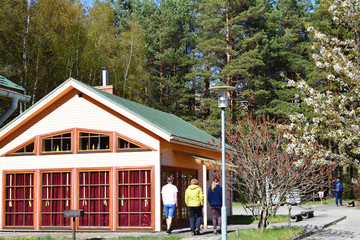Fototapeta na wymiar Group of people walking away next to wooden colorful building and pine forest in cold sunny spring day. Lifestyle and family concept.