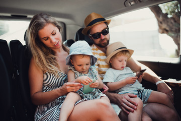 A young family with two toddler children in taxi on summer holiday.